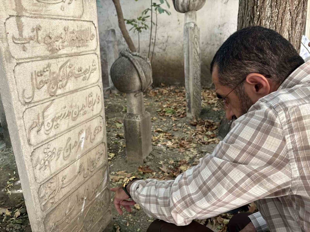 HAZİREDEKİ KABİRLERİN ÜZERİNDEKİ YAZILARI OKUYAN BİR VATANDAŞ