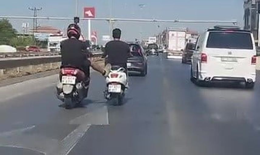 Yoğun trafikte ayağıyla motosikleti iten sürücü kameraya takıldı