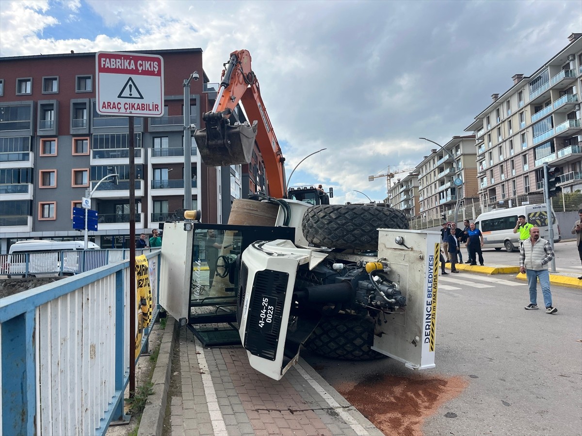 Kocaeli'nin Derince ilçesinde, seyir halindeki tırın üzerinden yola devrilen iş makinesindeki kişi...
