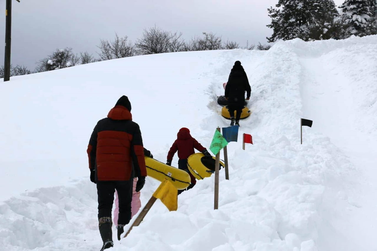 ABANT GÖLÜ MİLLİ PARKI'NDA KÖYLÜLERİN OLUŞTURDUĞU DOĞAL PİSTTE ÇOCUKLAR ŞAMBRELLERLE KAYARAK KARIN...