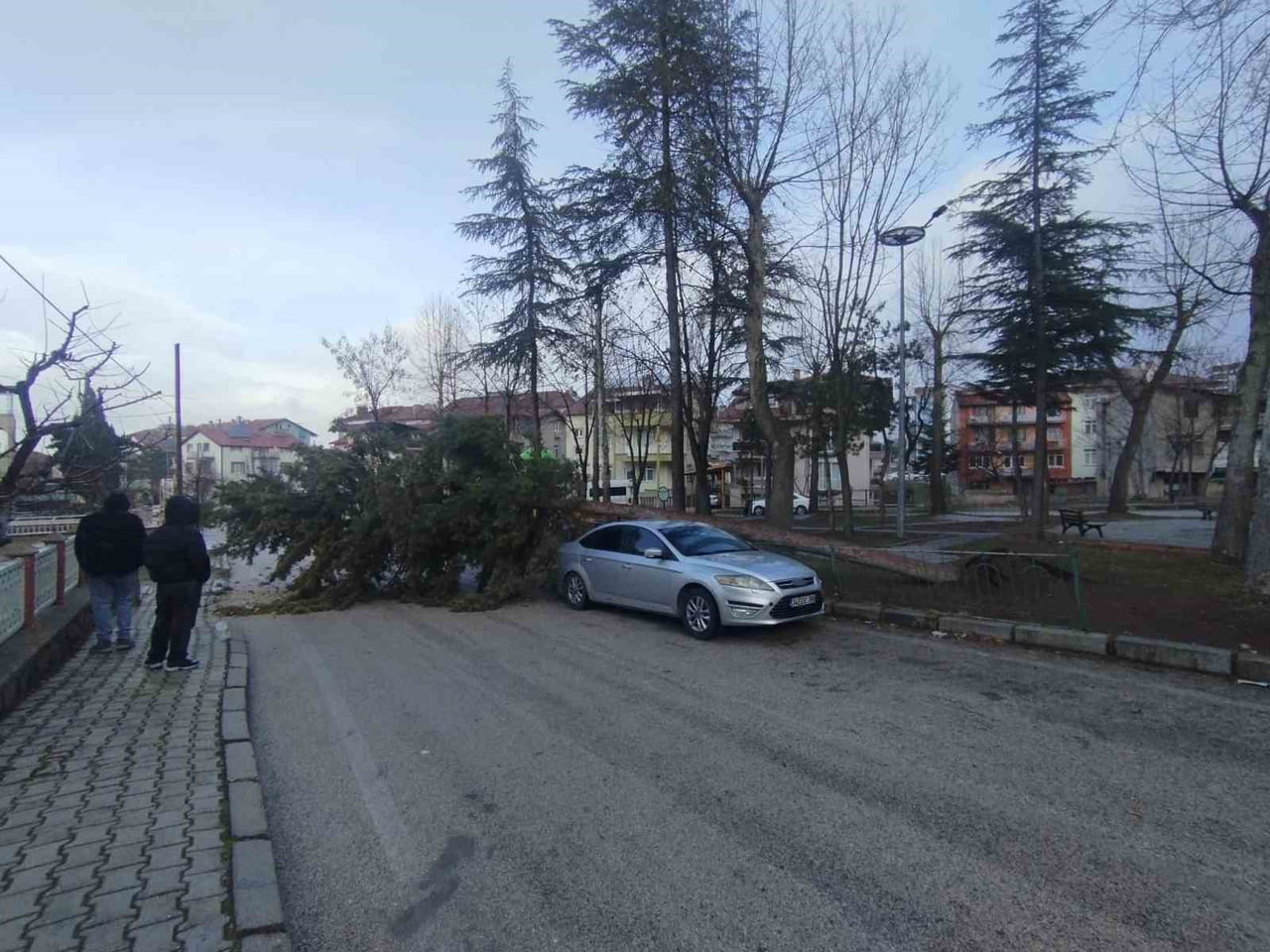 ISPARTA’DA ETKİSİNİ ARTIRAN FIRTINA, BİR AĞACI KÖKÜNDEN SÖKEREK PARK HALİNDEKİ ARACIN ÜZERİNE...